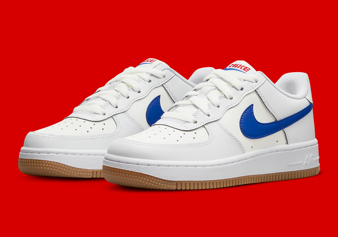 Logo màu xanh blue làm điểm nhấn nổi bật trên nền trắng kem của đôi giày sneaker Nike Air Force 1 Low "University Red"